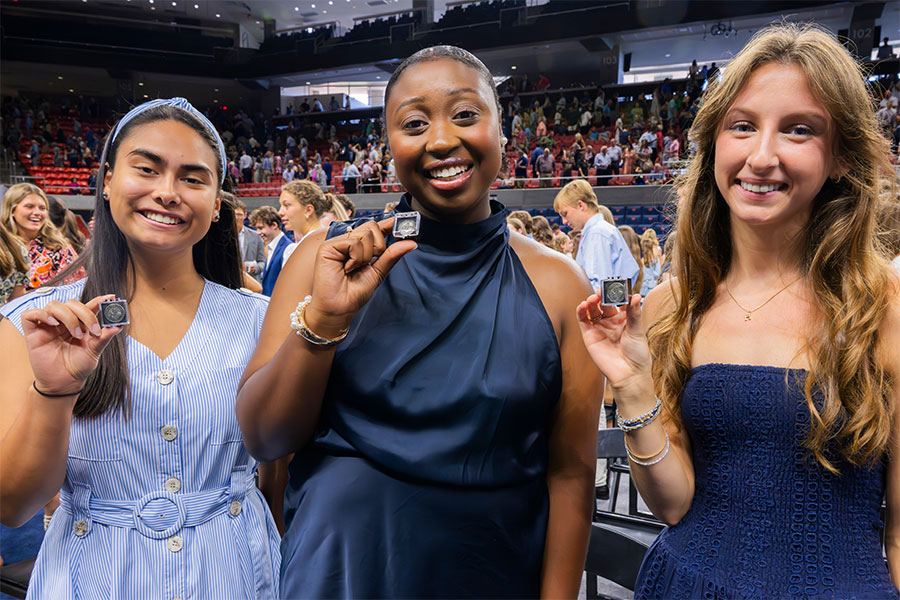 Three students holding Honors Induction pin at 2025 ceremony