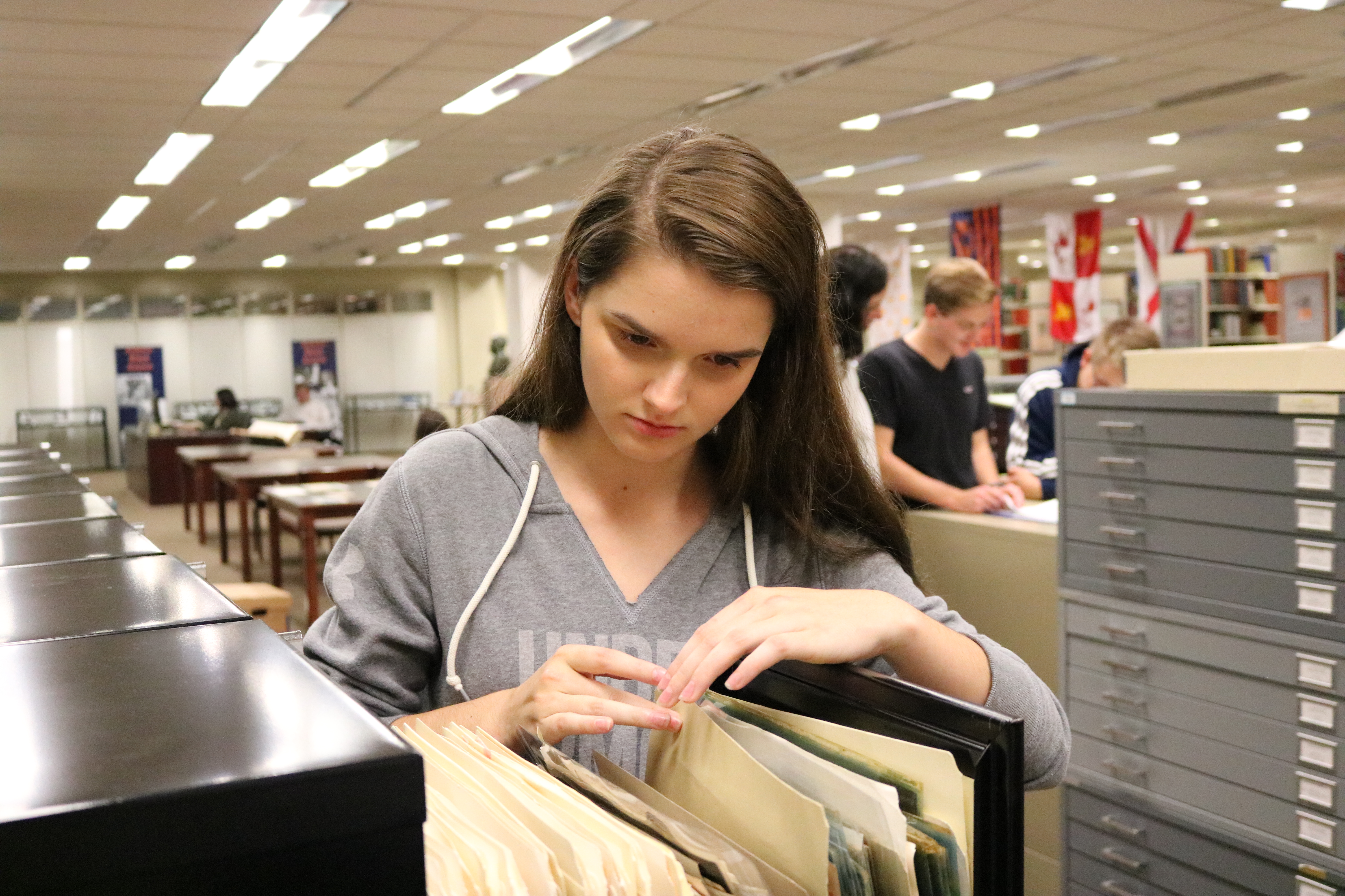 Girl looks through a file folder in a library